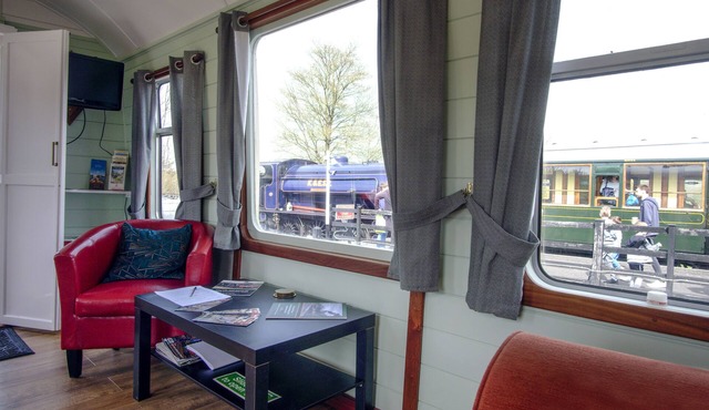 A carefully converted heritage railway coach in the countryside.